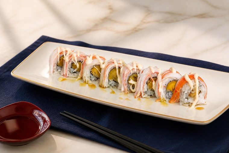 A roll topped with crabmeat and mango sauce